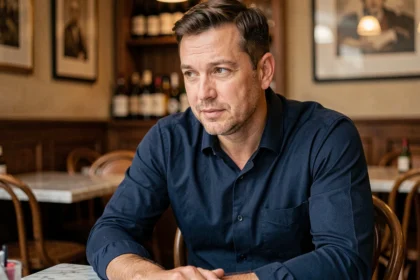 Homme en chemise bleue dans un café parisien évoquant une conversation intime sur sa vie de couple
